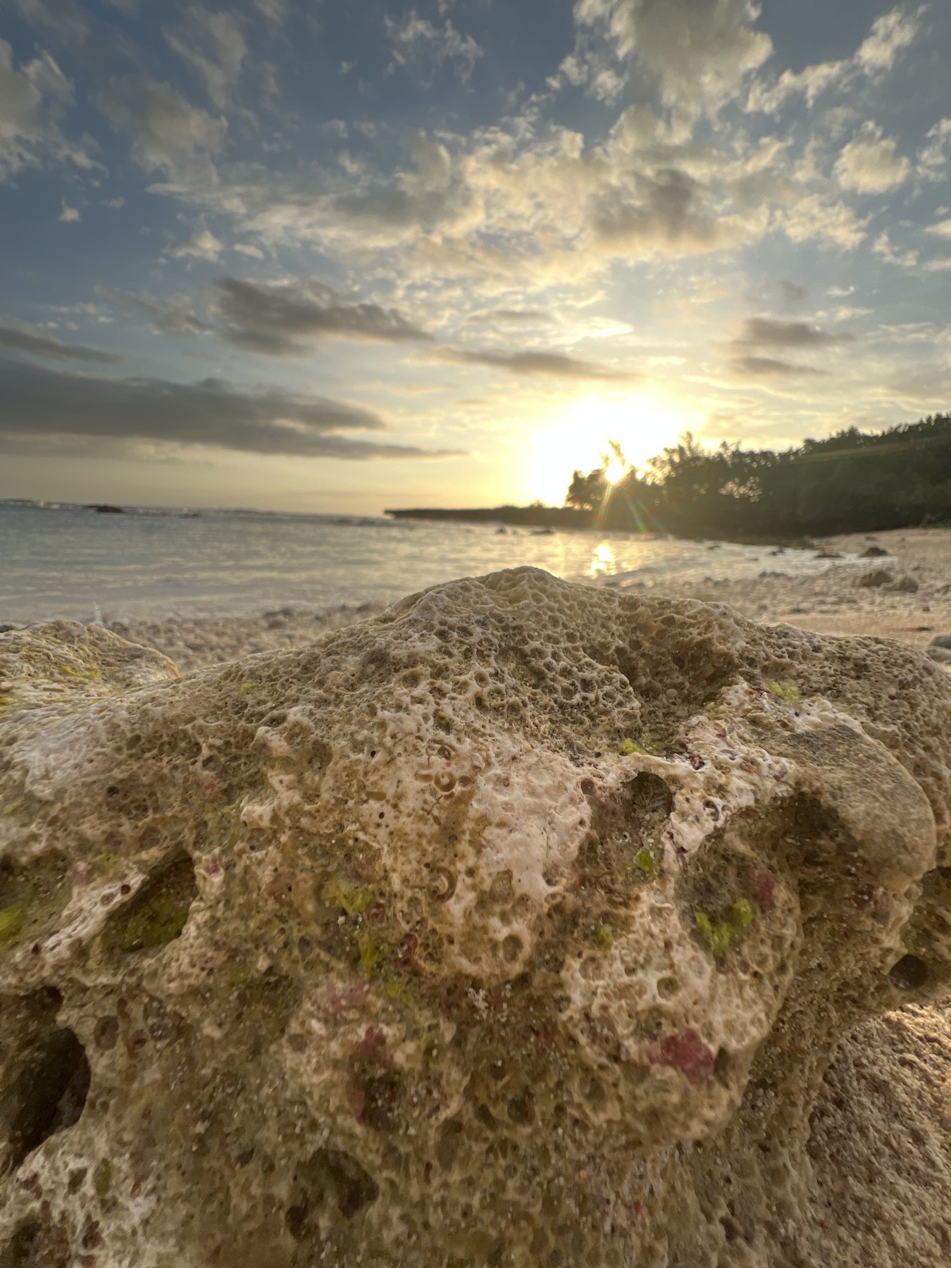 Sunset over the sea with a textured coastal rock in the foreground